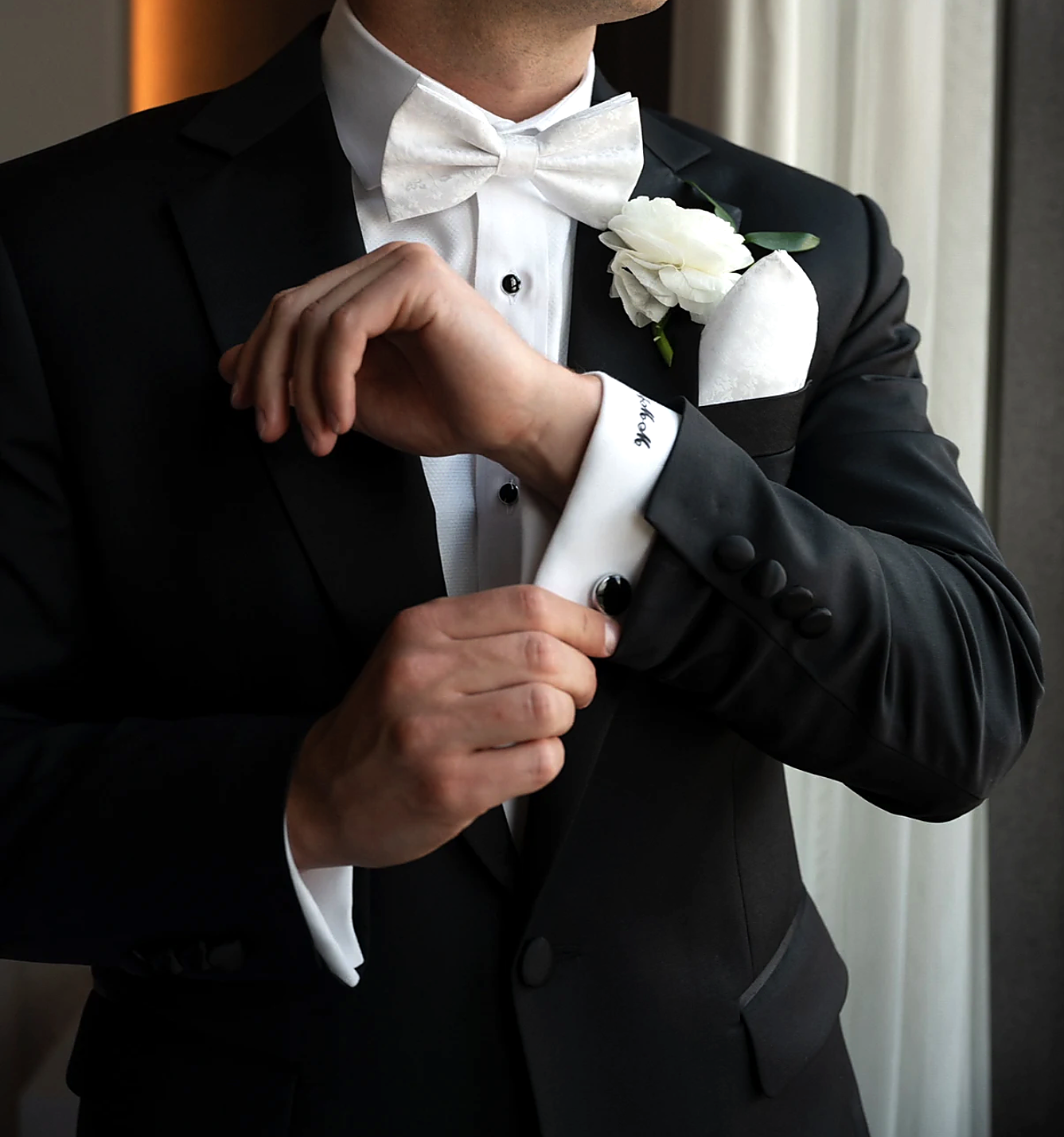 Hand-tailored tuxedo with white bowtie, boutonniere, and cufflink detail